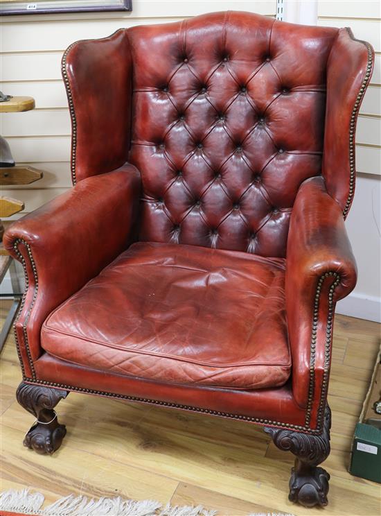 A George II style red leather buttoned wing armchair, ball and claw feet